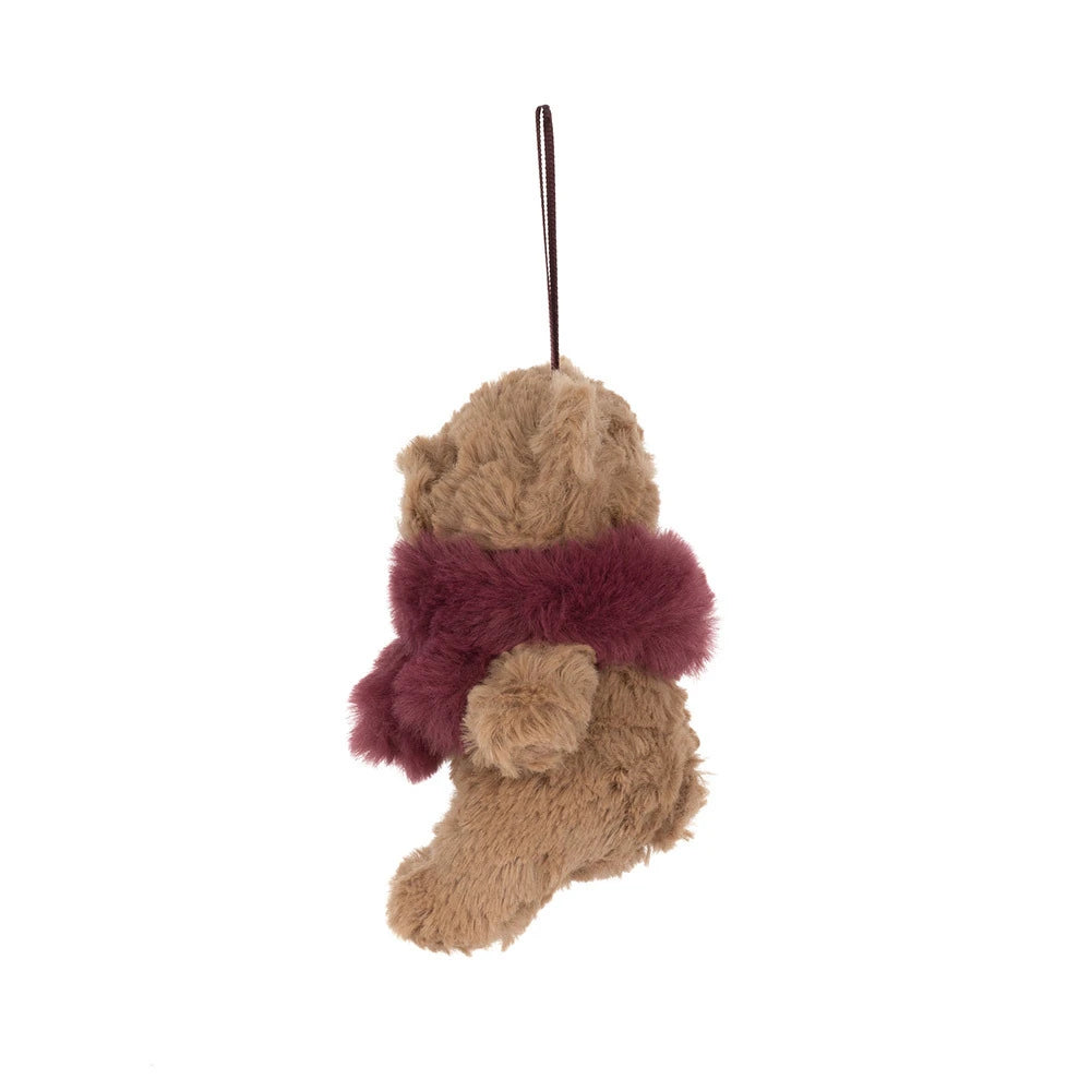 The side of a  small plush teddy bear ornament or hanging decoration in tan with a fuzzy burgundy scarf and a matching hanging loop, shown on a plain white background.