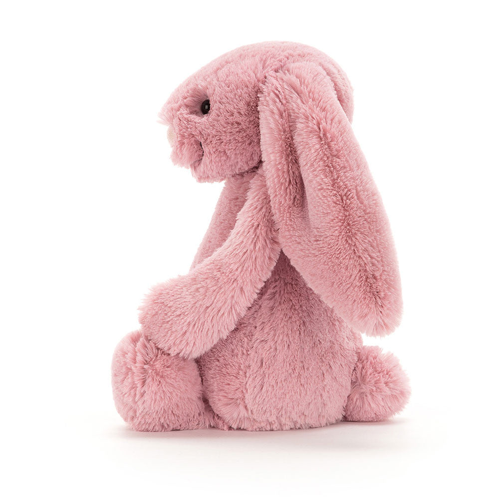 Side of a tulip pink bunny with a gentle expression, sitting upright.