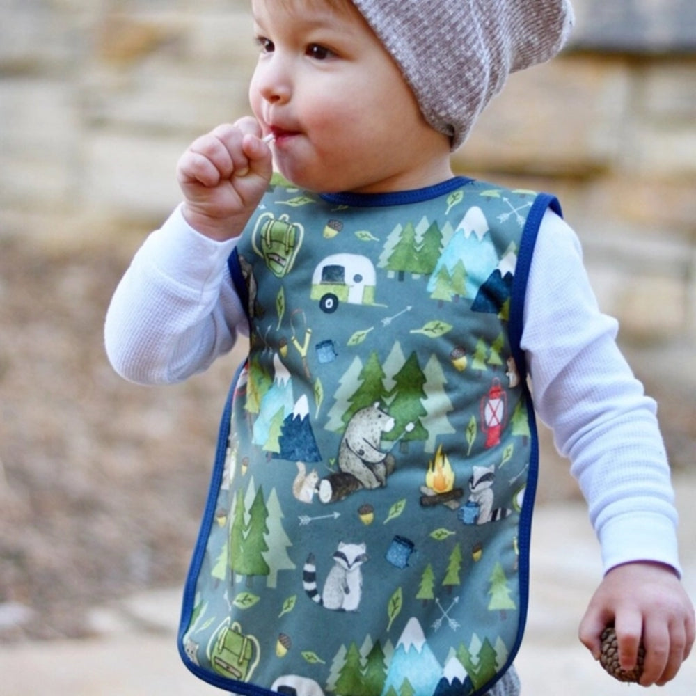 Baby wearing a bib with nature-themed print outdoors