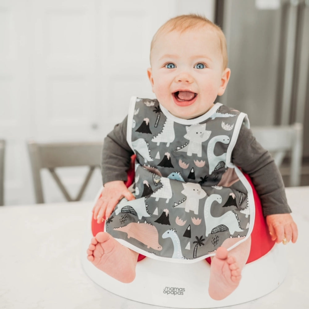 Baby wearing a gray bib with animal patterns sitting in a high chair.
