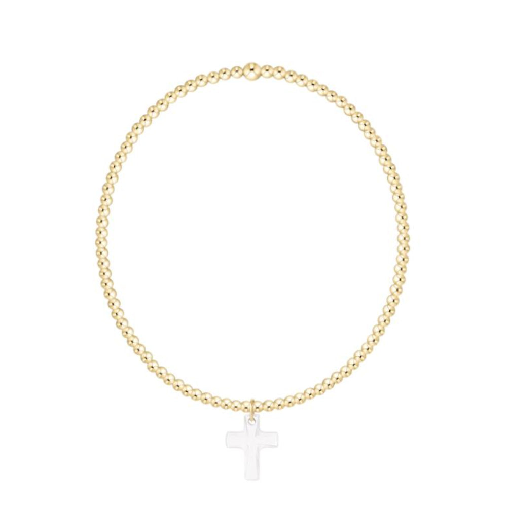 Gold bracelet with a white cross charm on a white background
