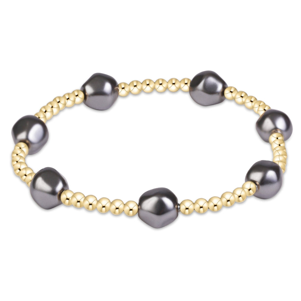 A beaded stretch bracelet featuring large, irregular dark gray freshwater pearls and small, polished gold-toned beads, shown on a plain white background.