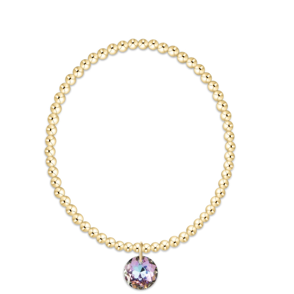 A gold beaded stretch bracelet with a single round iridescent crystal charm, displayed on a clean white background.