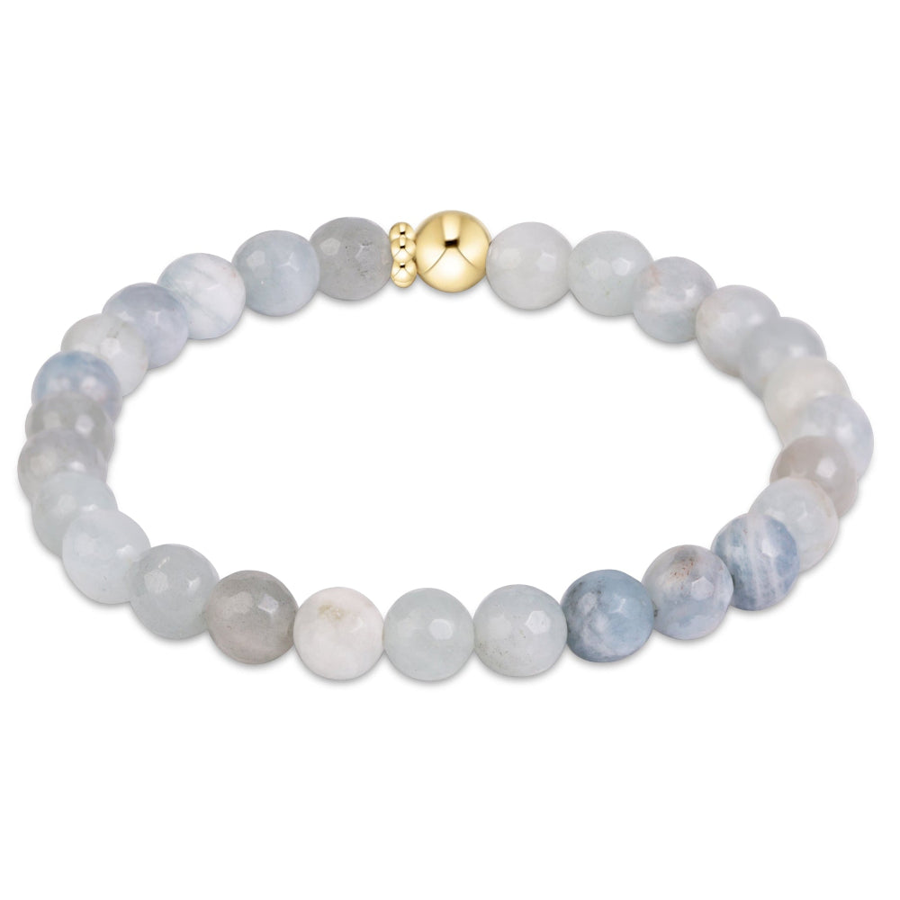 A beaded bracelet made of round light gray and pale blue marbled beads, featuring a polished gold-toned central bead clasp, shown on a plain white background.