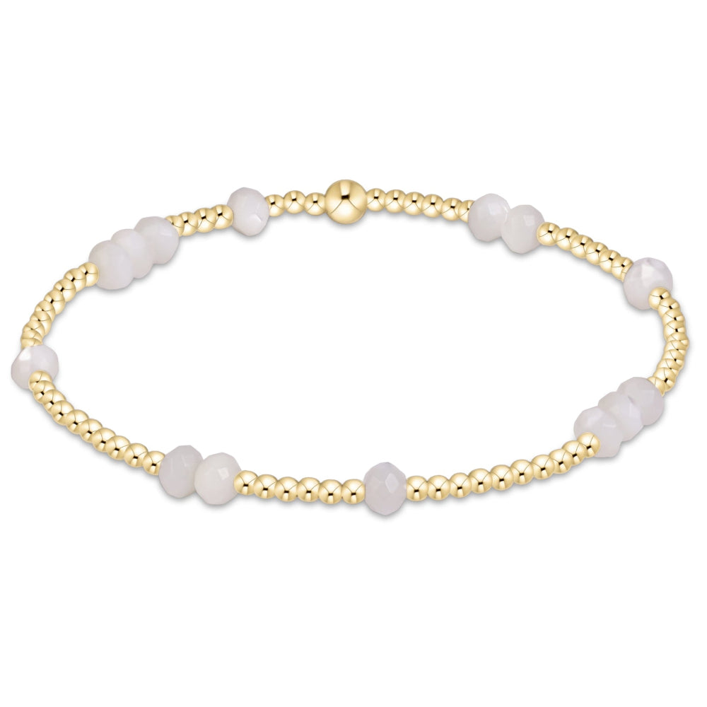 A delicate beaded bracelet featuring alternating smooth pale pinkish-white beads and gold-toned metallic beads, displayed on a clean white background.