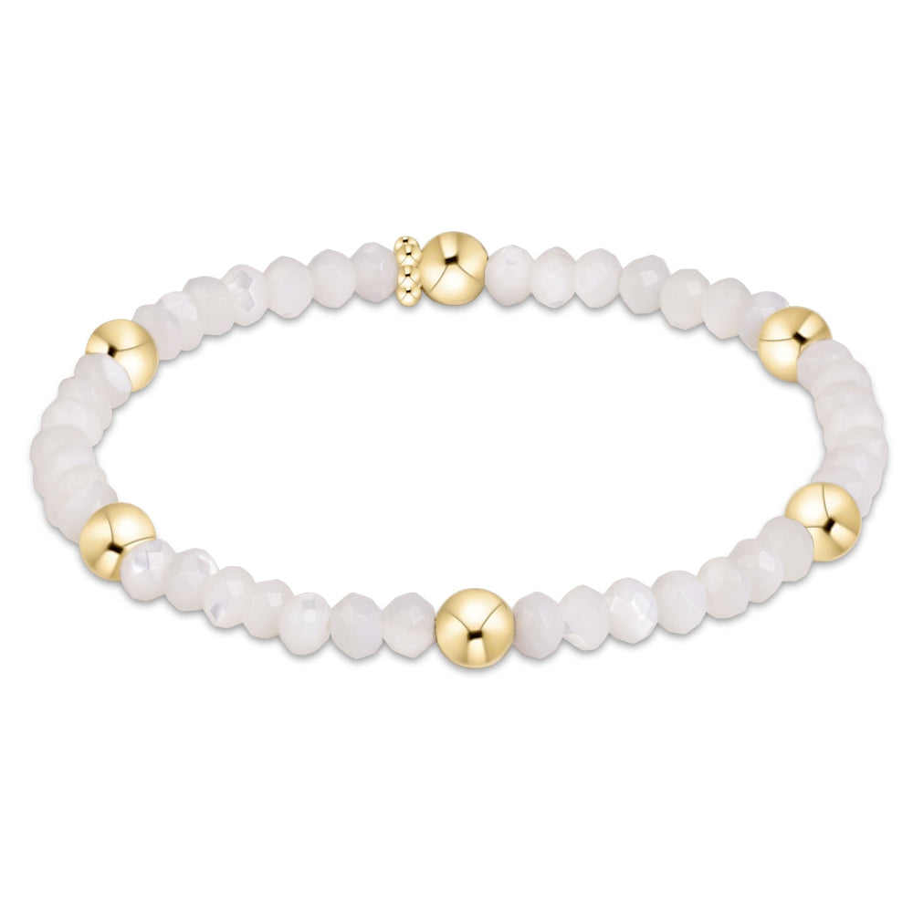 A beaded stretch bracelet featuring white marbled beads and polished gold spacer beads, displayed on a clean white background.
