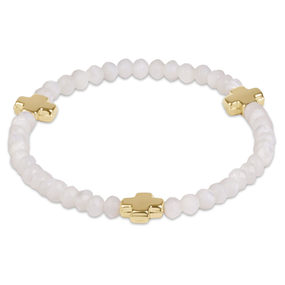 A beaded stretch bracelet featuring matte white round beads and three polished gold cross charms, displayed on a clean white background.