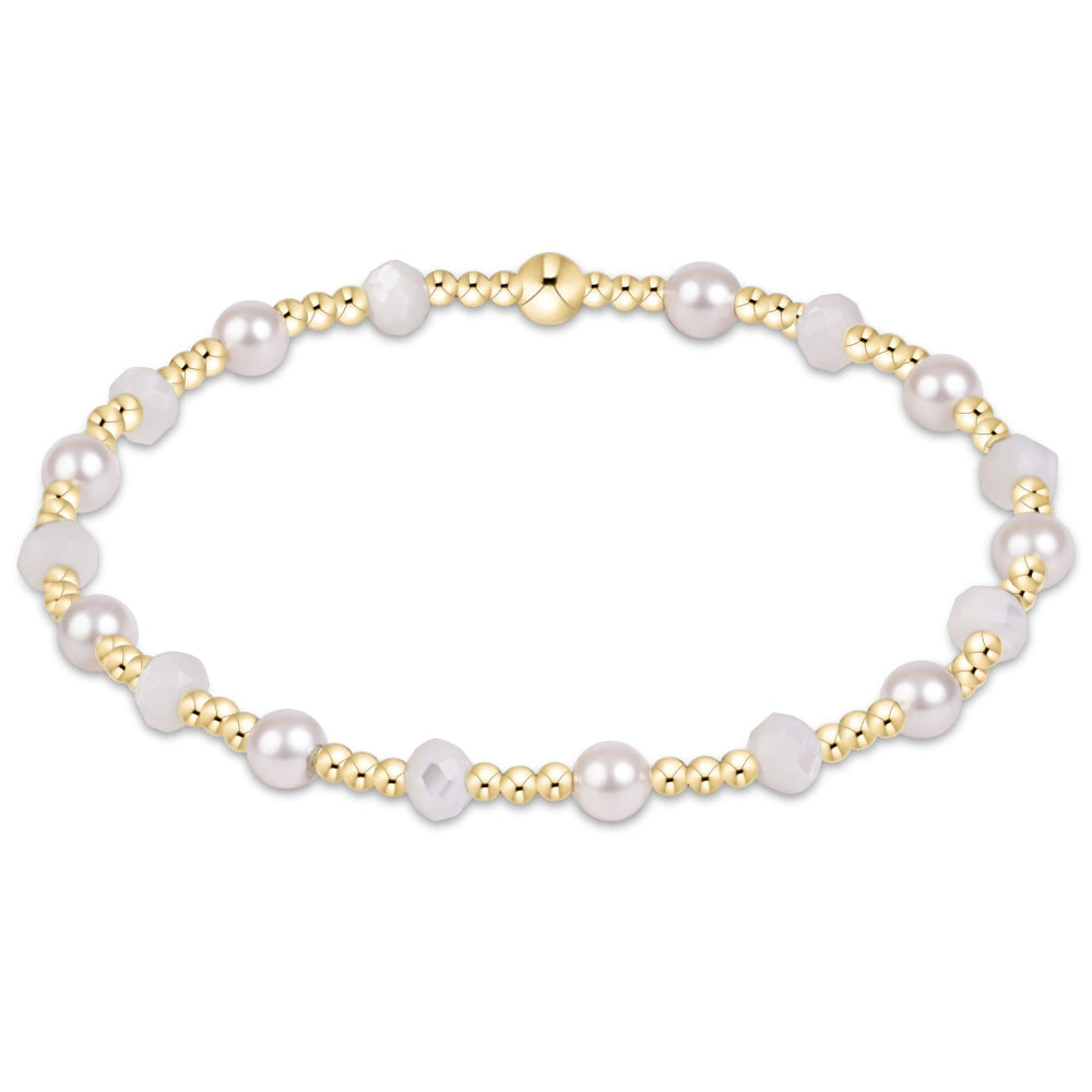 A delicate beaded bracelet featuring white freshwater pearls and polished gold-tone beads, with a textured gold clasp, shown on a plain white background.