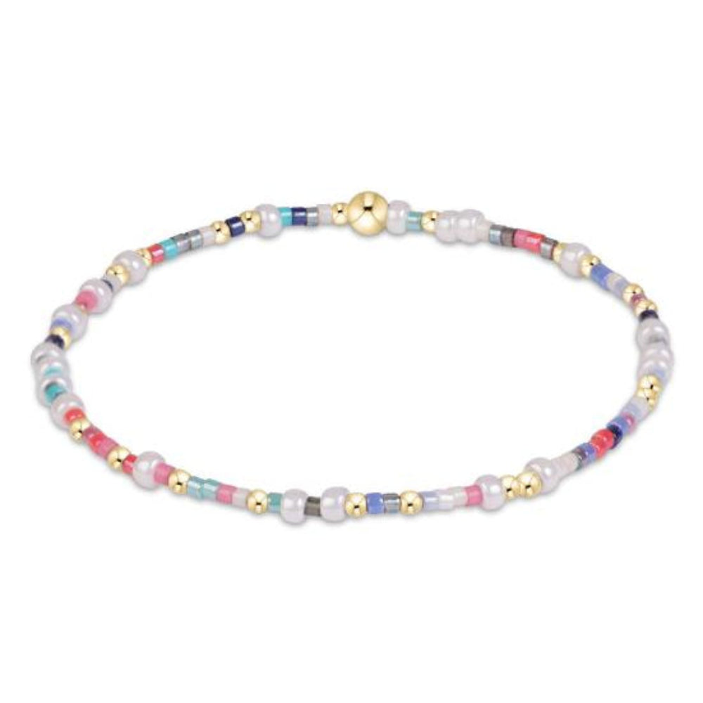 A delicate beaded bracelet with white pearl-like beads, small gold spacer beads, and multicolored accent beads in pink, blue, and teal, shown on a plain white background.