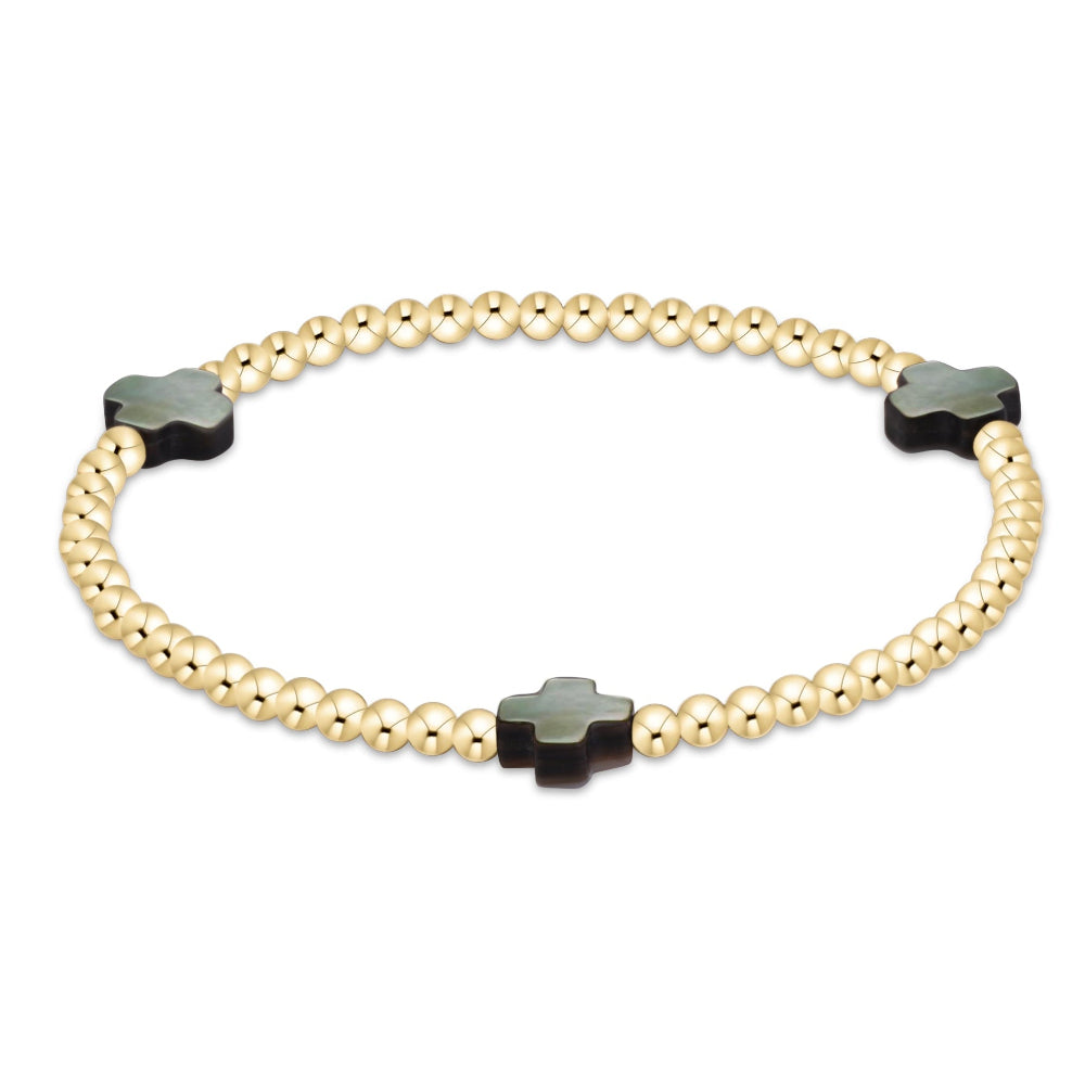 A gold beaded bracelet with three black cross-shaped beads spaced along the band, shown on a plain white background.