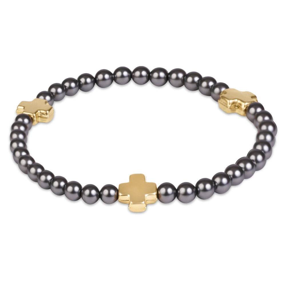 A beaded bracelet featuring dark gray pearls and polished gold-tone cross-shaped charms, displayed on a clean white background.