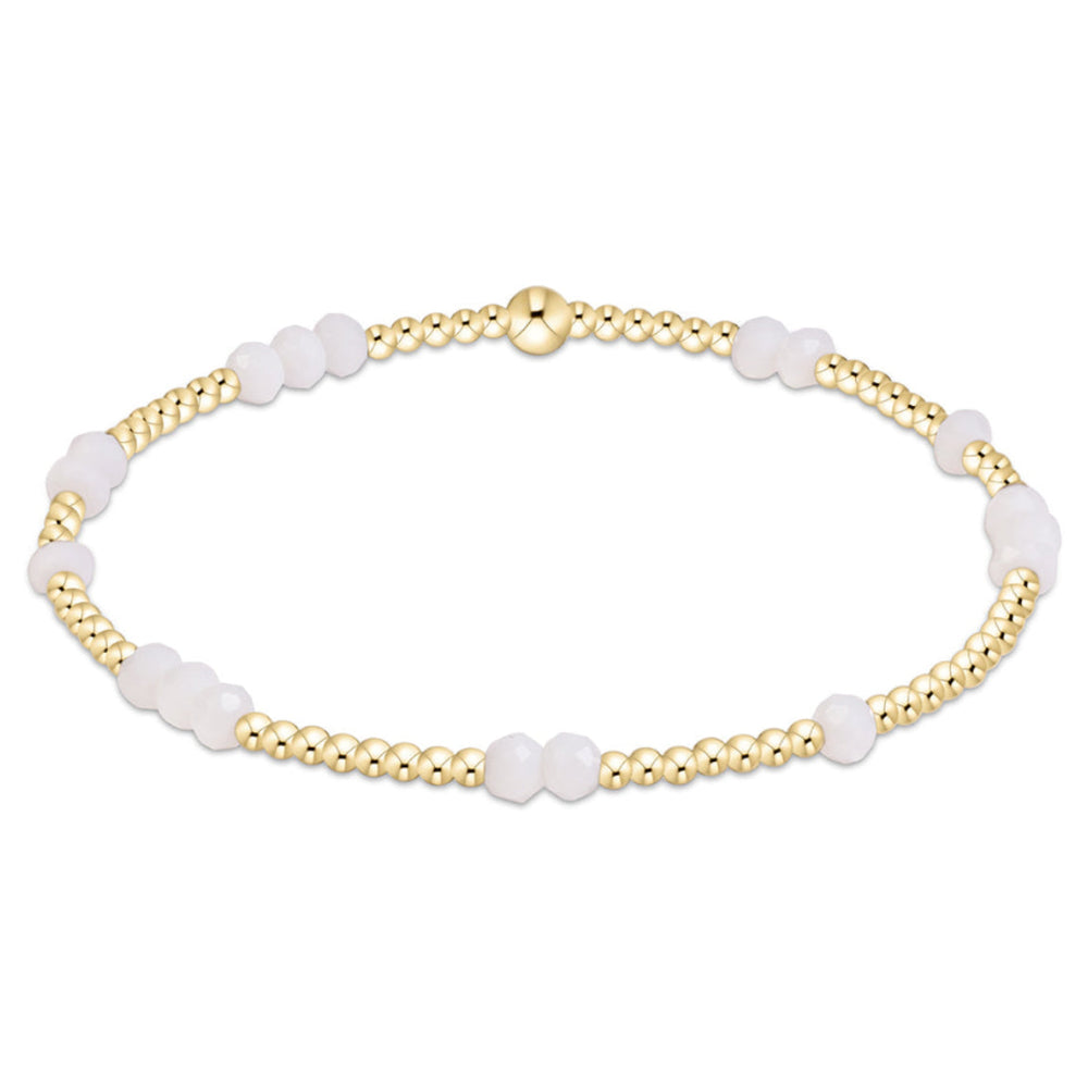A delicate gold chain bracelet featuring alternating small gold beads and smooth, opaque white oval beads, displayed on a clean white background.