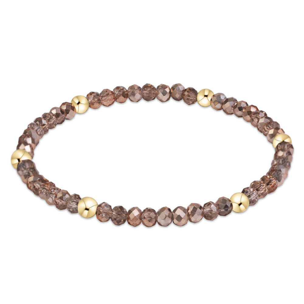 A beaded stretch bracelet featuring faceted brown smoky glass beads and polished gold spacer beads, displayed on a clean white background.