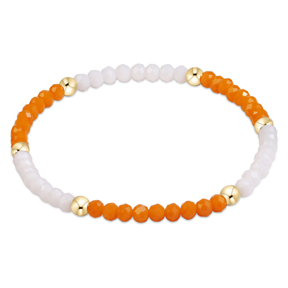 A beaded stretch bracelet featuring alternating sections of faceted orange beads and smooth white beads, separated by small metallic gold spacer beads, shown on a plain white background.