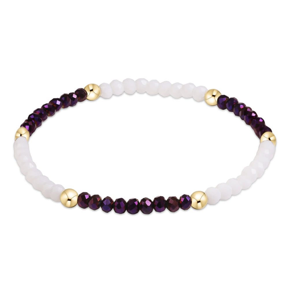 A beaded stretch bracelet featuring a matte white front section, a row of faceted dark purple beads, and small polished gold spacer beads, shown on a plain white background.