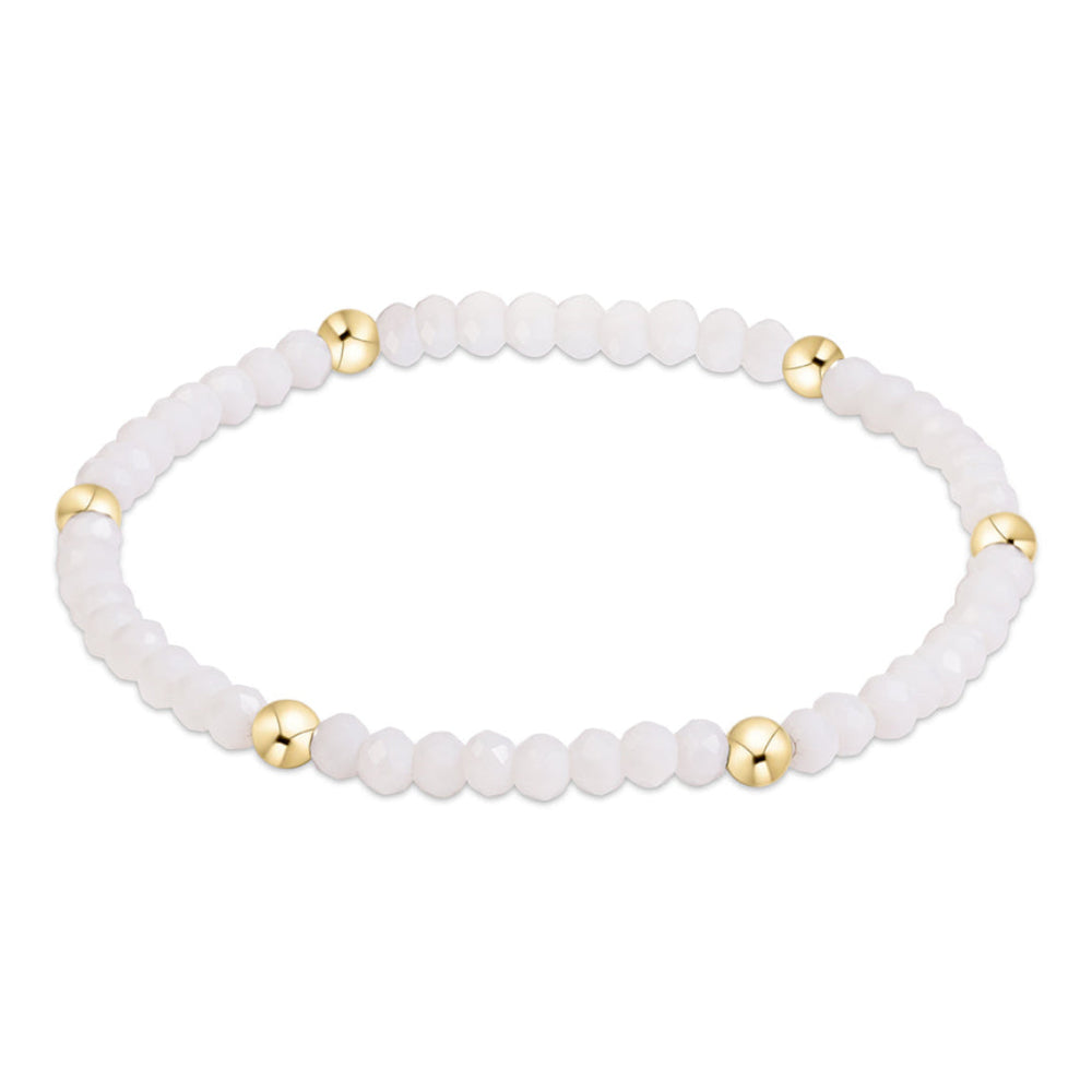 A beaded stretch bracelet featuring white faceted beads and five polished gold spacer beads, displayed on a clean white background.