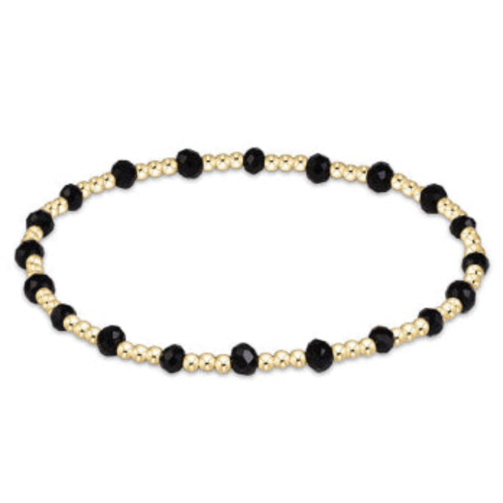 A beaded stretch bracelet featuring alternating black faceted beads and small gold metallic beads, displayed on a clean white background.