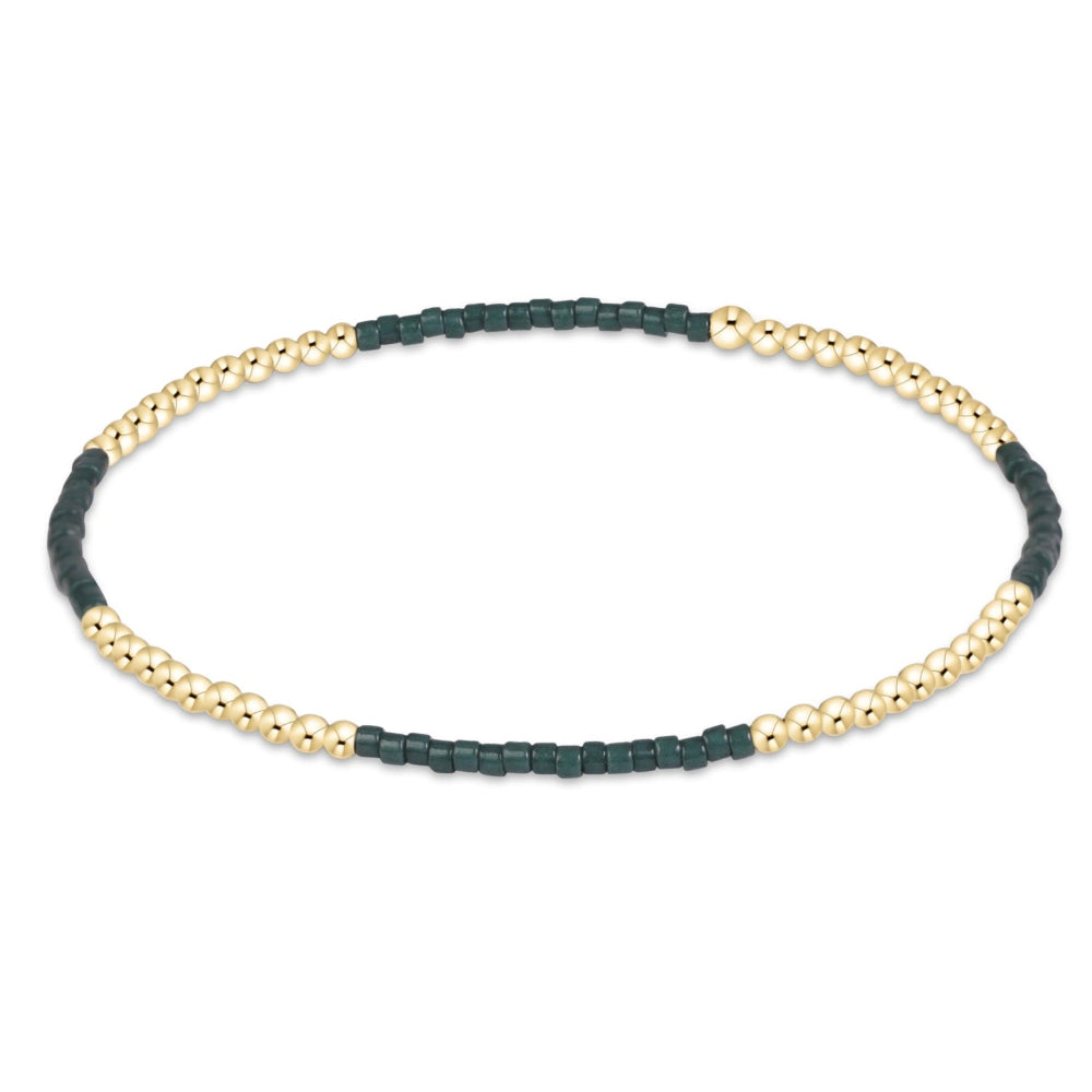 A delicate beaded bracelet with alternating sections of dark green cord and gold-toned metallic beads, displayed on a clean white background.