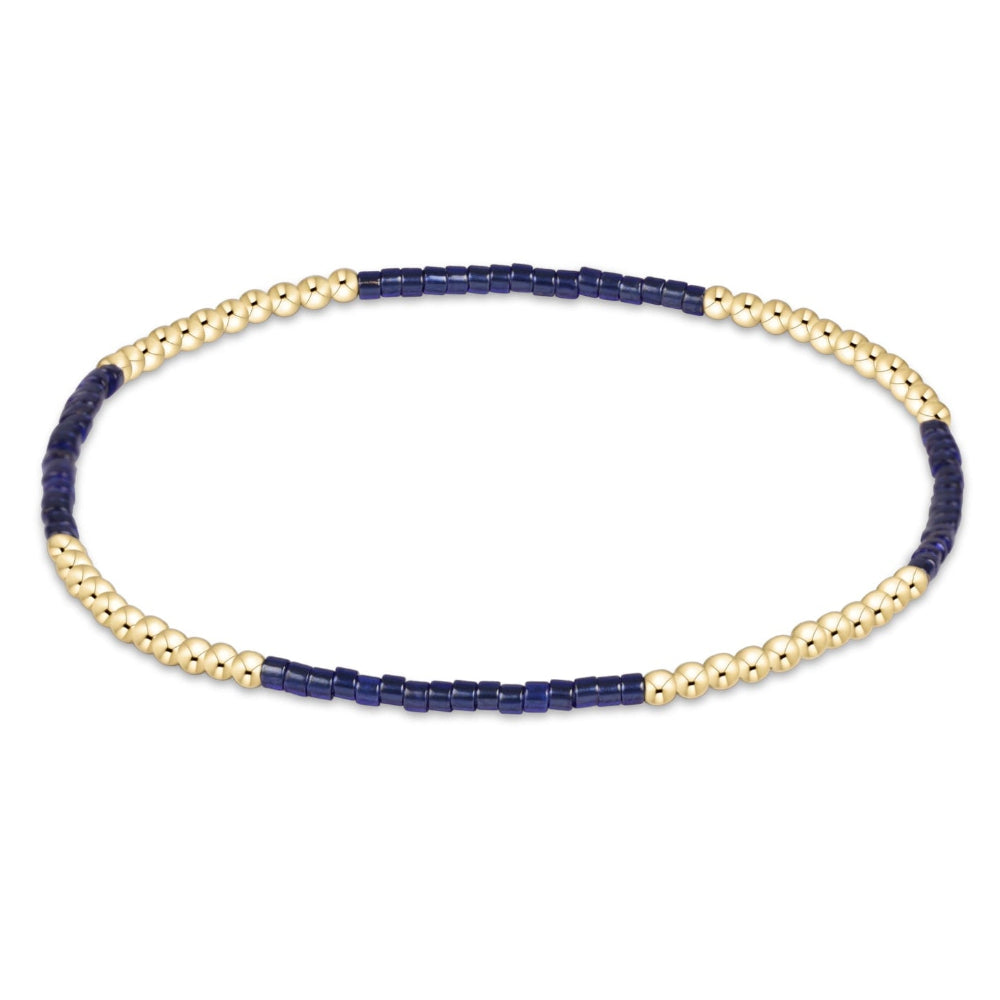A beaded stretch bracelet featuring alternating sections of small dark navy blue beads and polished gold-tone round beads, displayed on a clean white background.