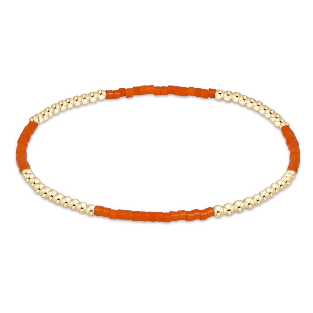 A beaded stretch bracelet featuring alternating sections of textured orange cylindrical beads and smooth cream-white spherical beads, displayed on a clean white background.