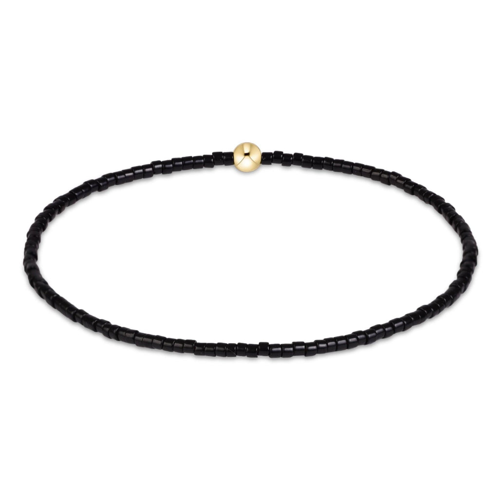 A delicate black beaded bracelet with a polished gold spherical accent bead, displayed on a clean white background.