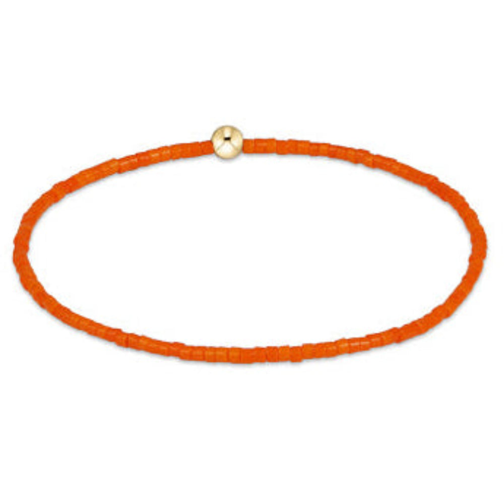 An orange beaded bracelet with a small gold-toned round bead clasp, displayed on a clean white background.