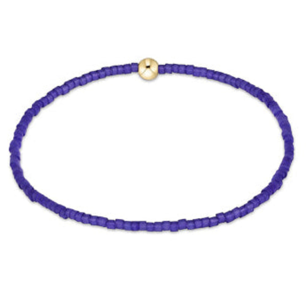 A beaded stretch bracelet made of small purple beads with a single gold-toned round clasp, shown on a plain white background.