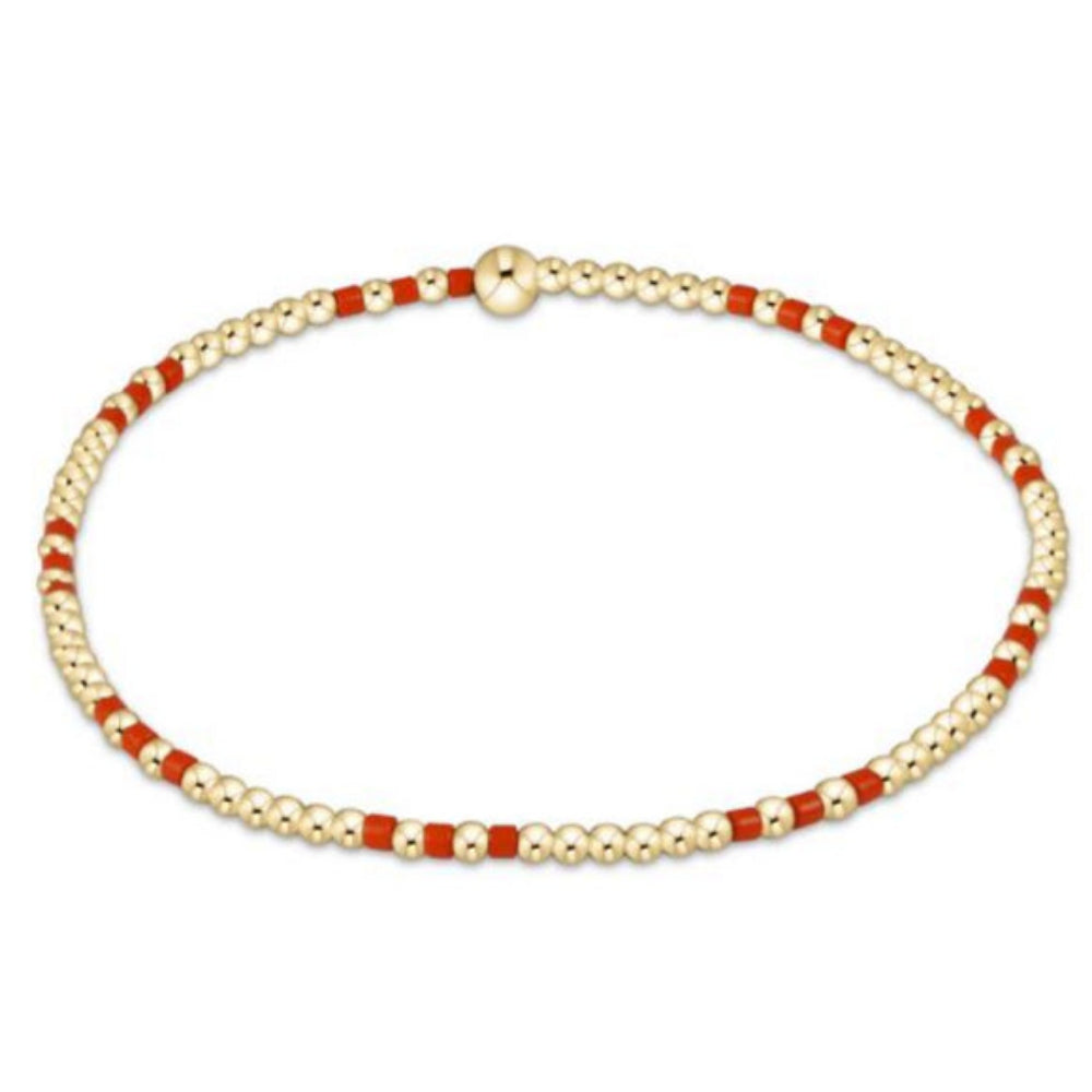 Bracelet with gold and red beads on a white background