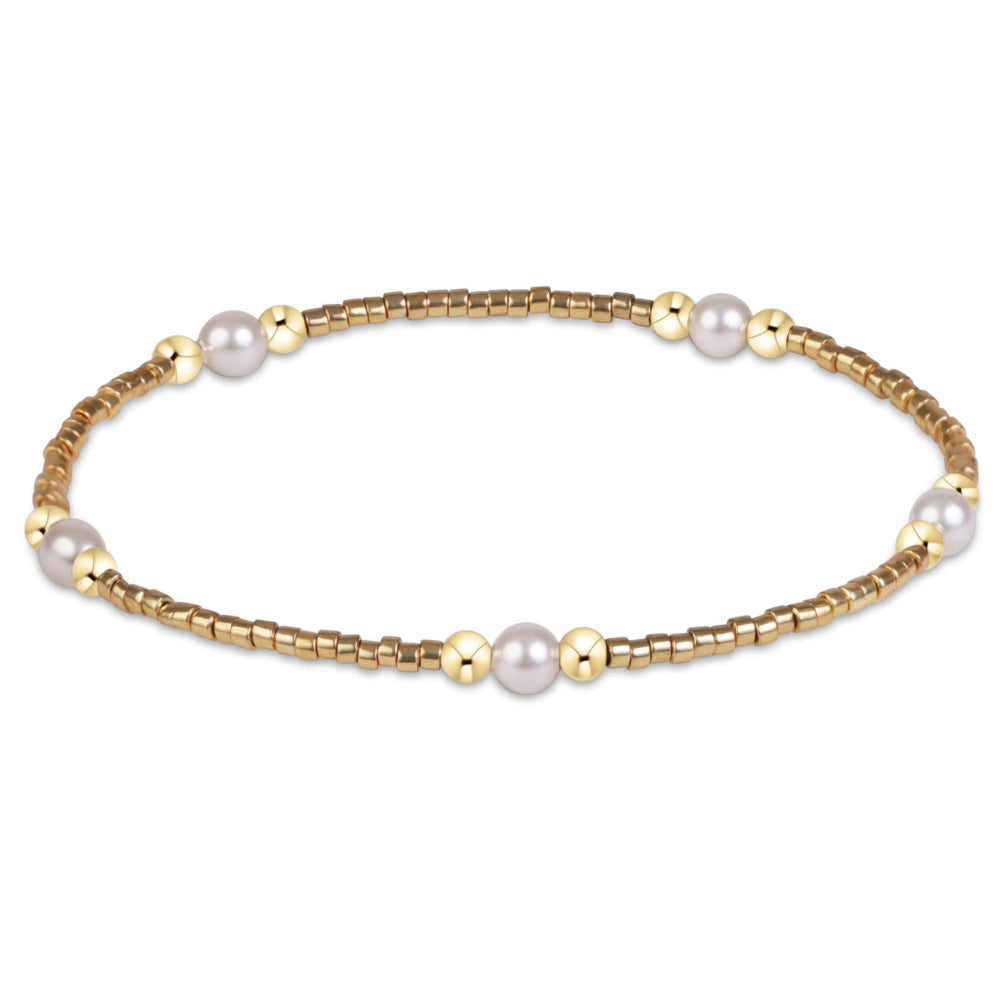 A delicate gold bead bracelet featuring five white pearl beads spaced evenly along the band, displayed on a clean white background.