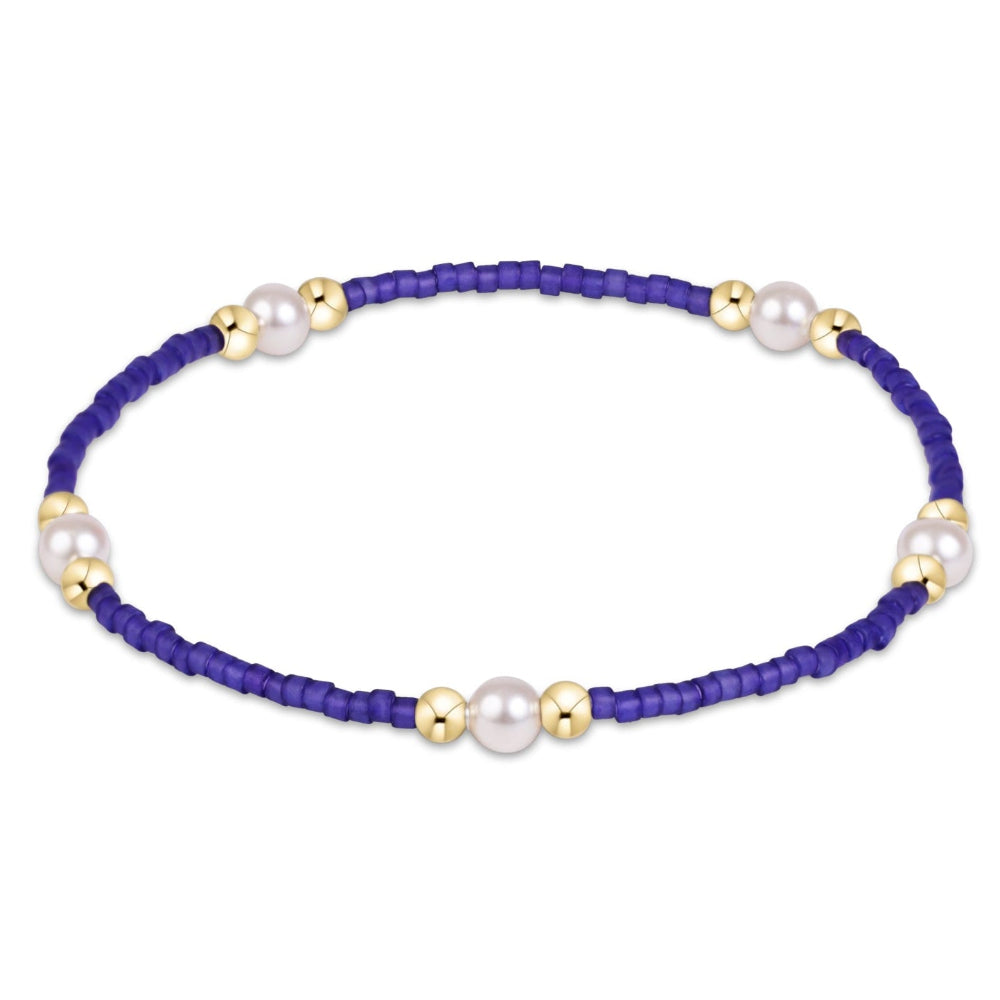 A beaded bracelet featuring a deep purple cord, accented with white freshwater pearls and polished gold spacer beads, shown on a plain white background.