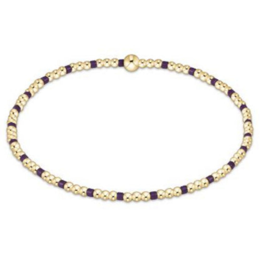 Gold and purple beaded braceleton a white background