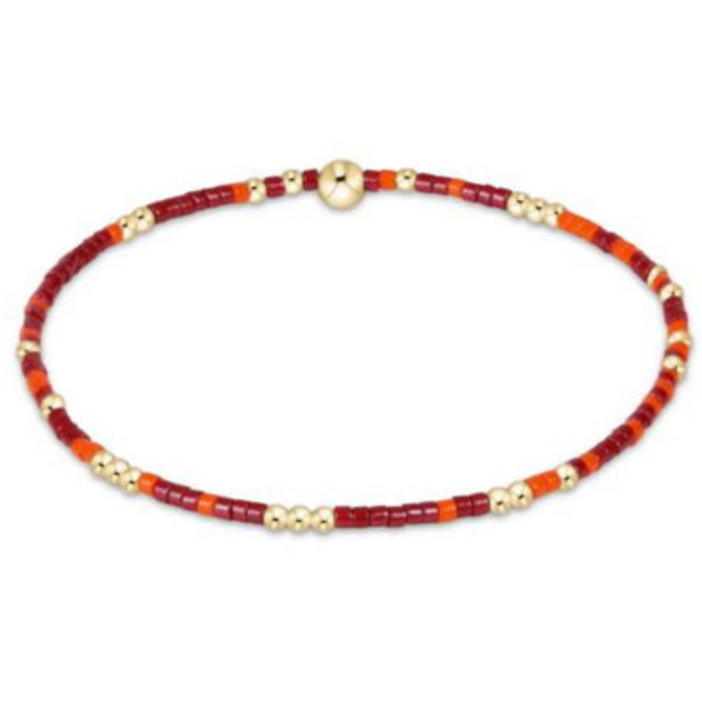 Bracelet with maroon, orange and gold beads on a white background