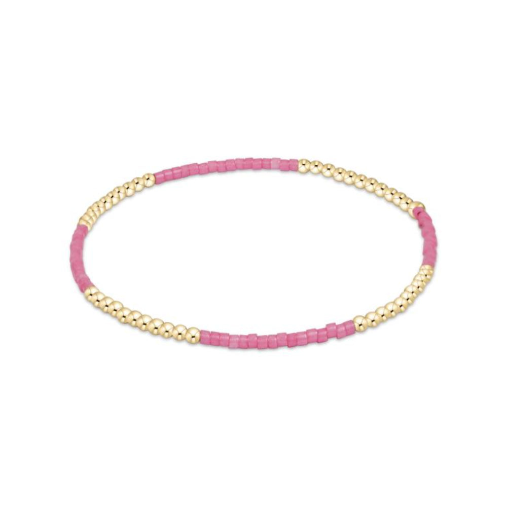 Pink beaded bracelet with gold accents on a white background