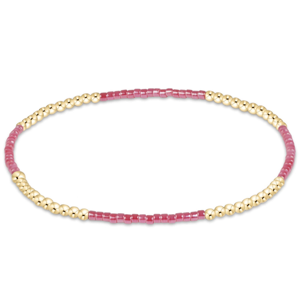 A delicate beaded stretch bracelet featuring alternating segments of small pink faceted beads and polished gold-toned round beads, displayed on a clean white background.