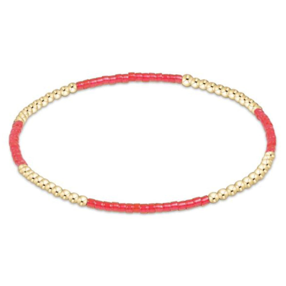 Bracelet with red beads and gold accents on a white background