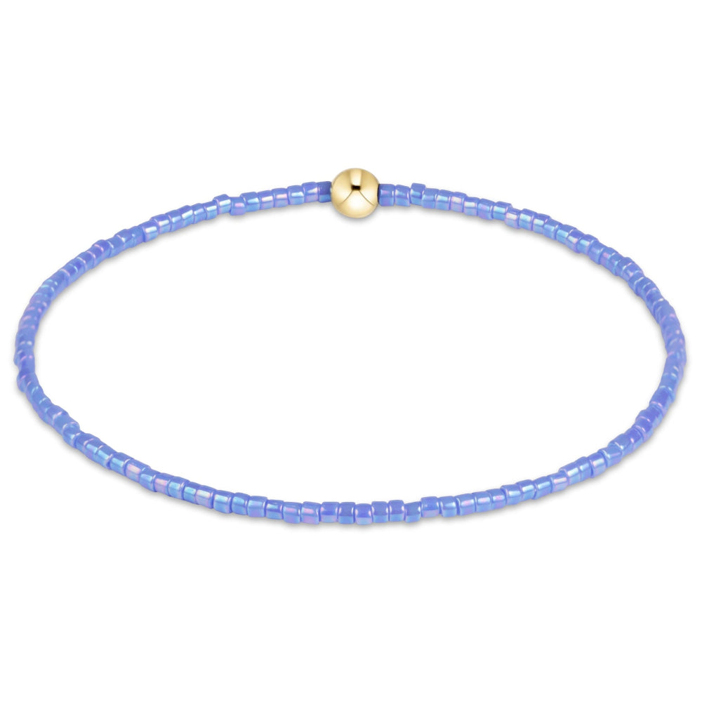 A delicate beaded bracelet made of small light blue faceted beads, featuring a single polished gold accent bead at the top, shown on a plain white background.