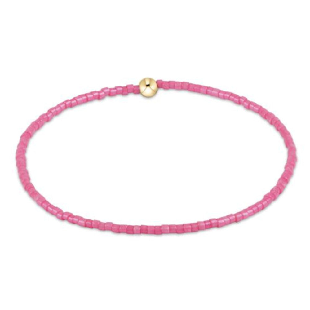 Pink beaded bracelet with a gold bead on a white background