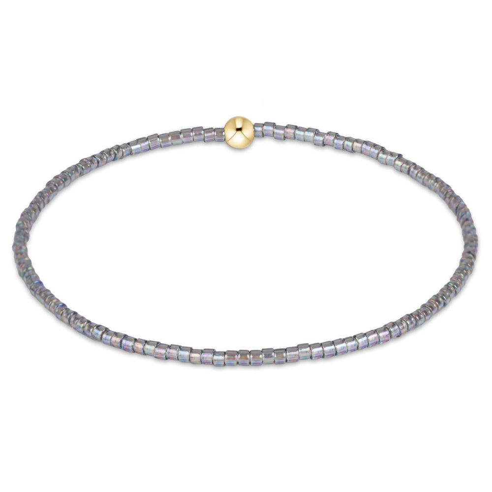 A delicate beaded bracelet with small, faceted gray beads and a single gold-toned round clasp, displayed on a clean white background.