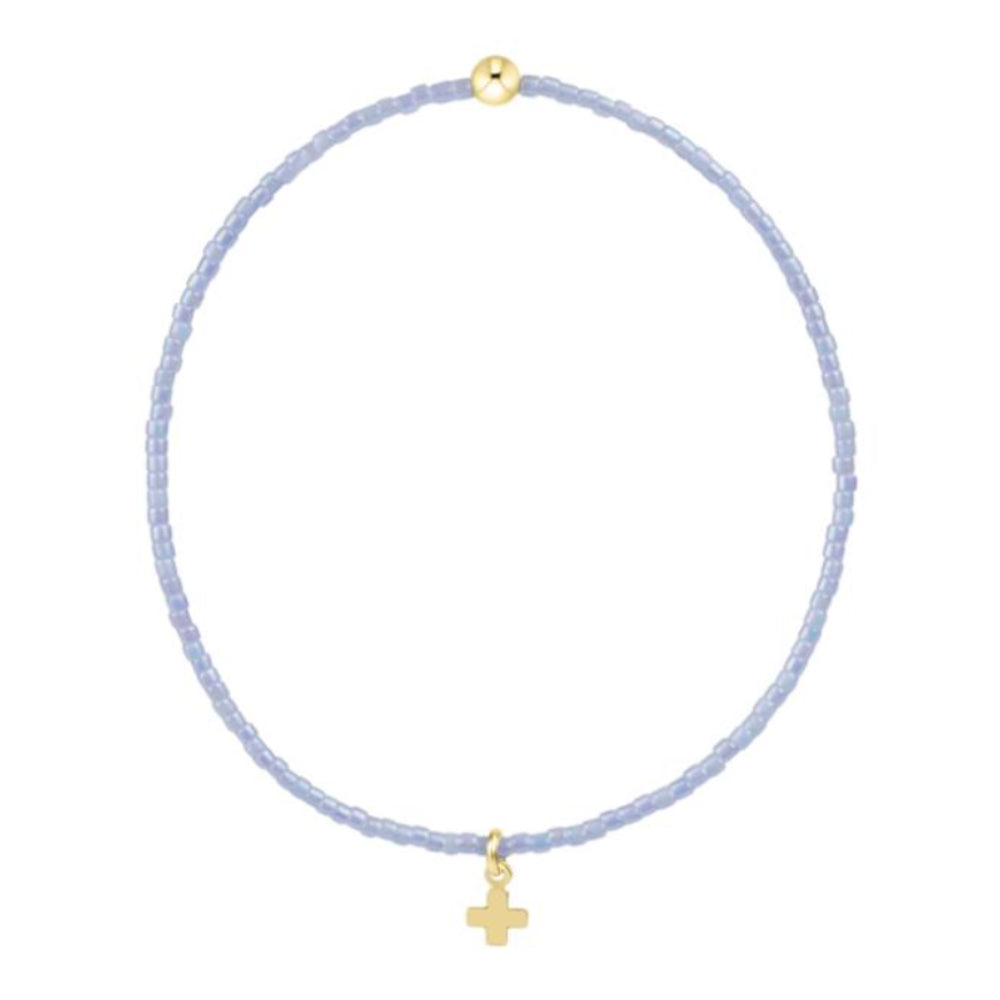 Bracelet with a light blue beads and gold cross charm on white background