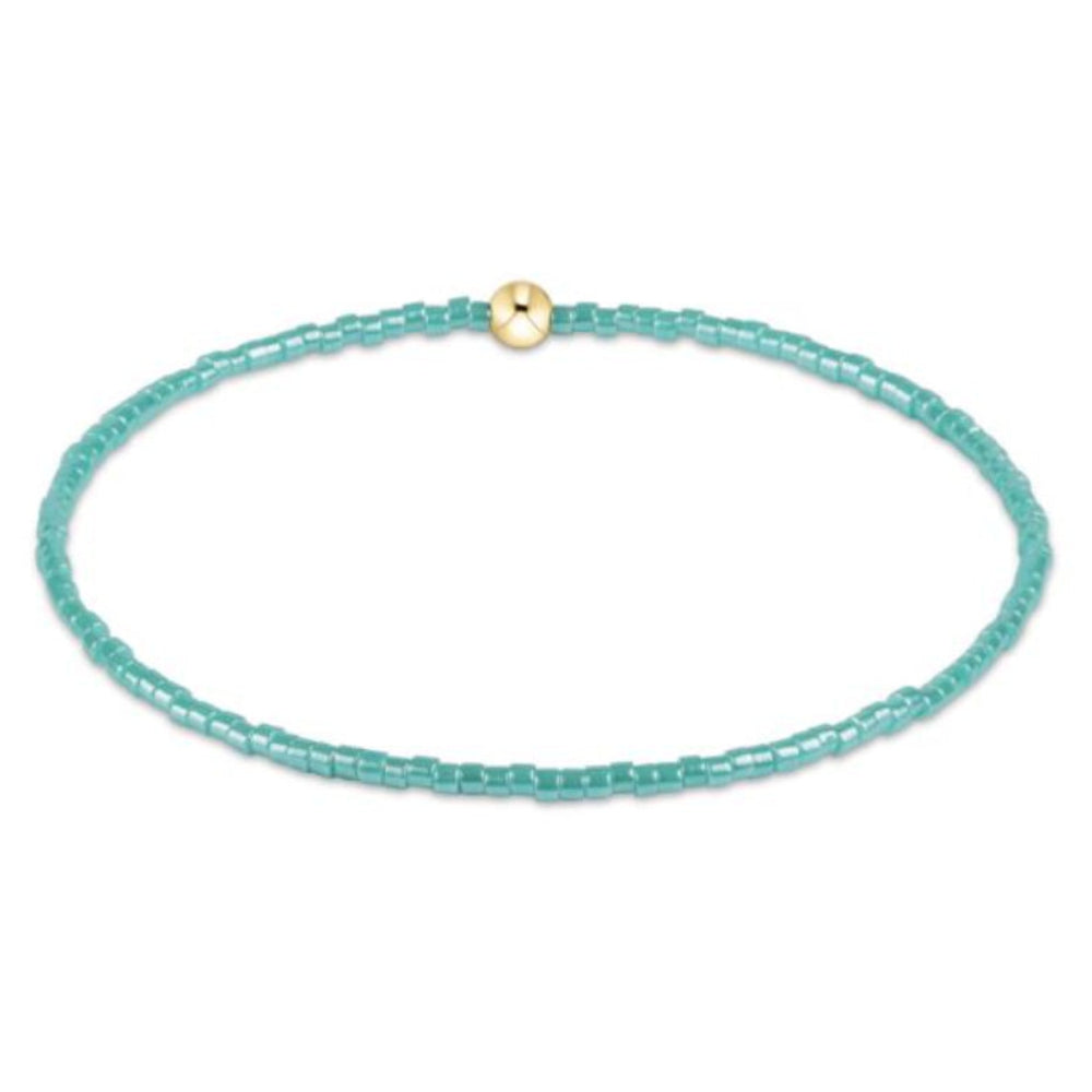 Turquoise beaded bracelet with a gold bead on a white background