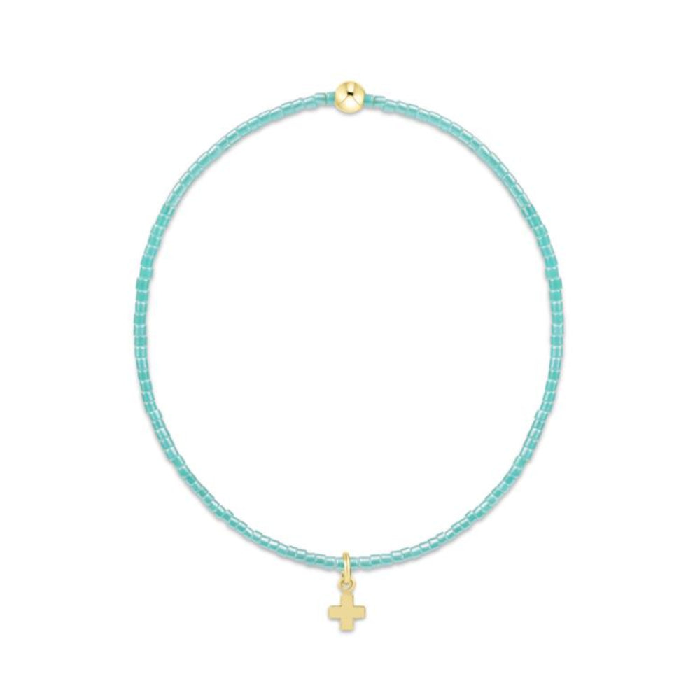 Turquoise beaded bracelet with a gold cross charm on a white background