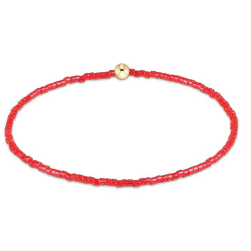 Red beaded bracelet with a gold bead on a white background