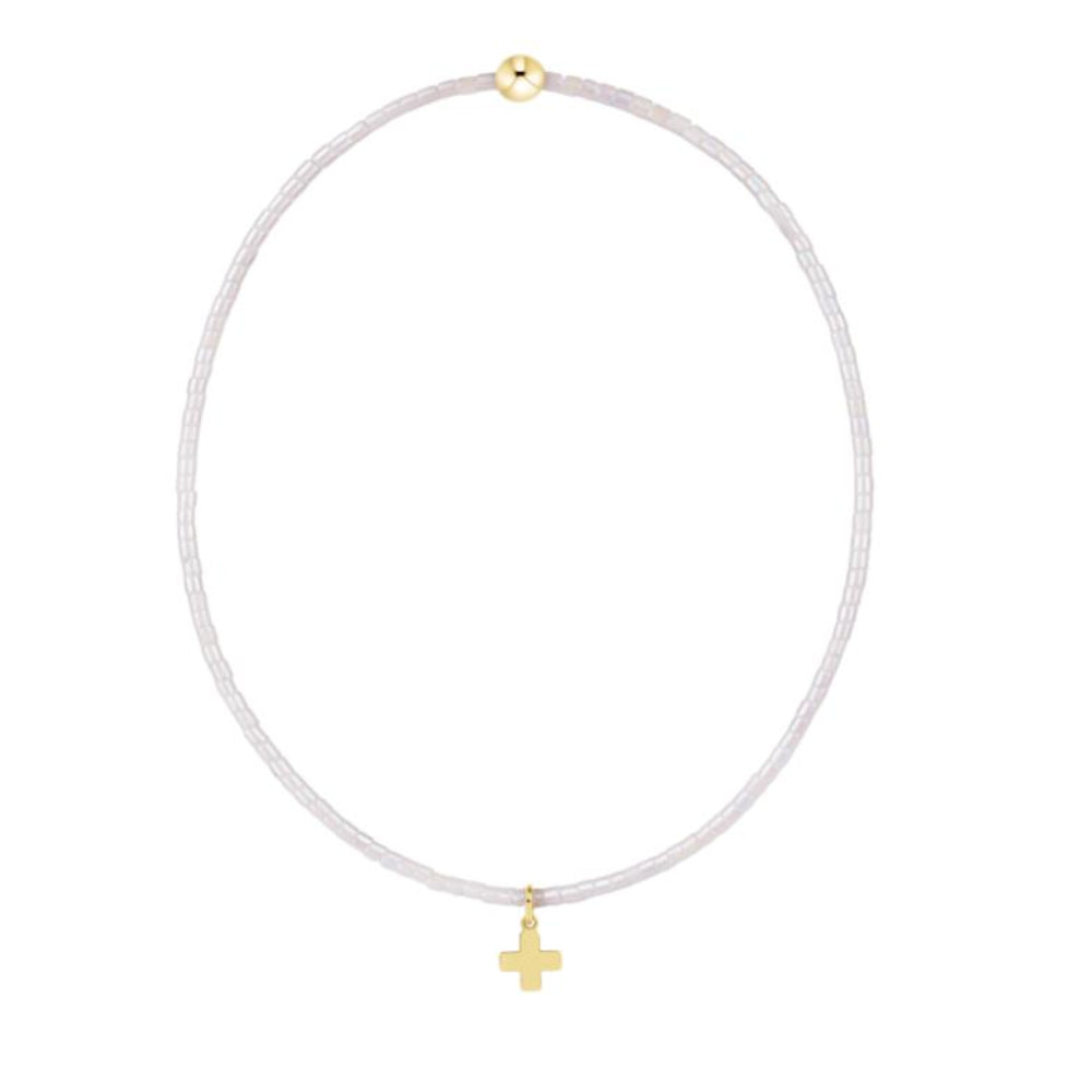 White beaded bracelet with gold cross charm on a white background