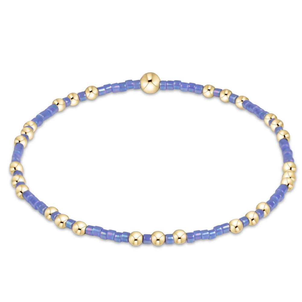A delicate beaded bracelet featuring light blue and polished gold-tone spacer beads, displayed on a clean white background.
