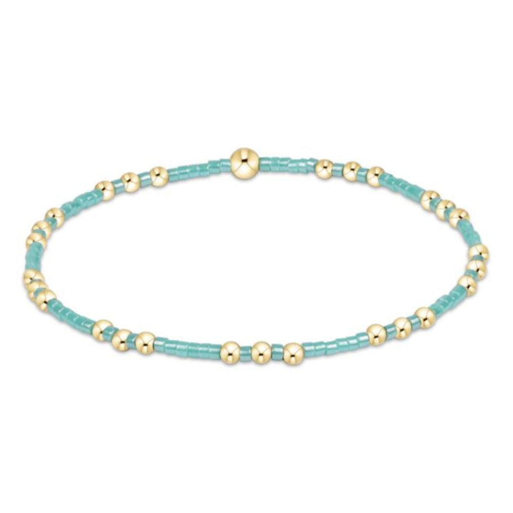 Turquoise beaded bracelet with gold beads on a white background