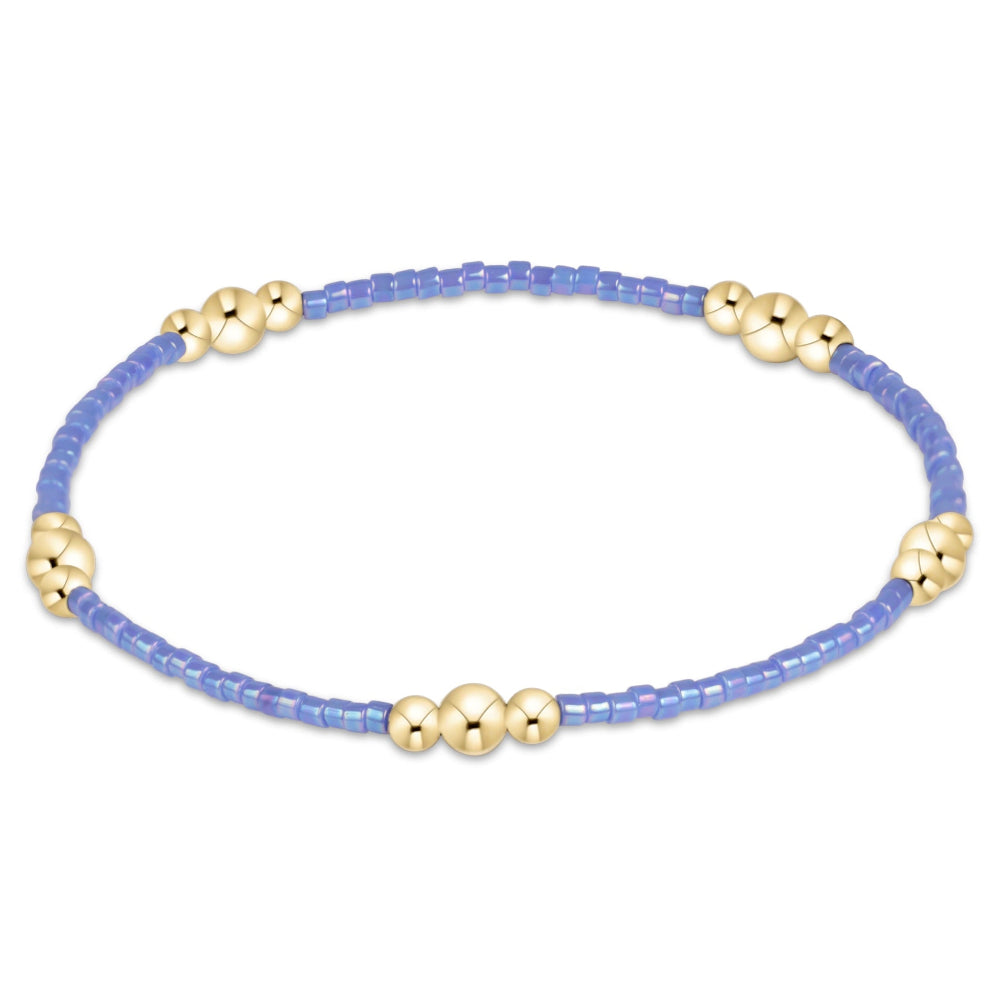 A delicate beaded bracelet featuring a light blue strand with small gold spacer beads, displayed on a clean white background.
