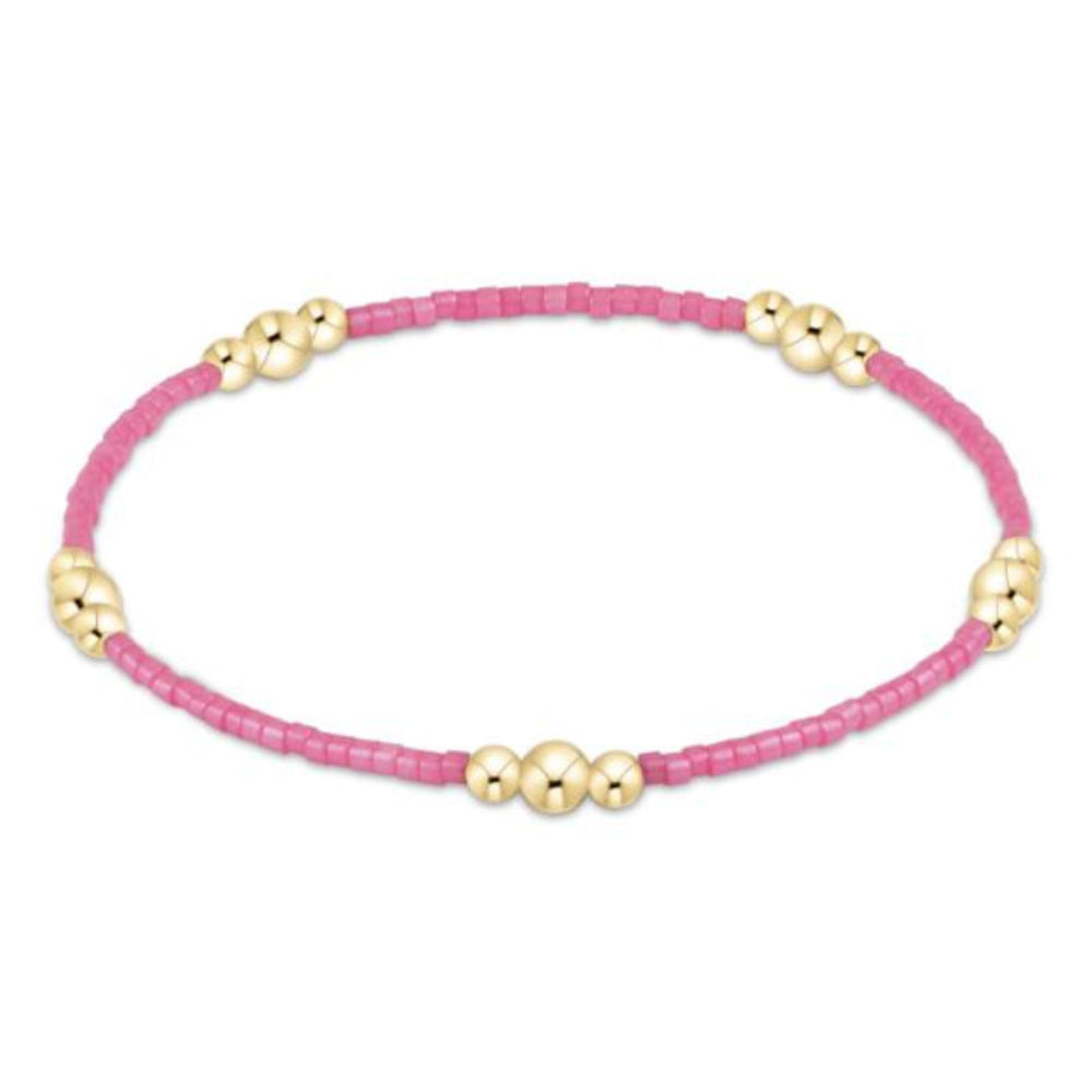 Pink beaded bracelet with gold beads on a white background