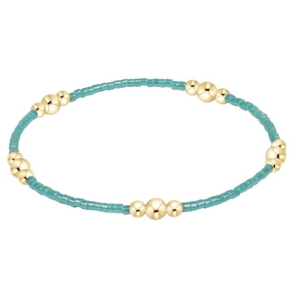 Bracelet with gold beads on a turquoise string against a white background