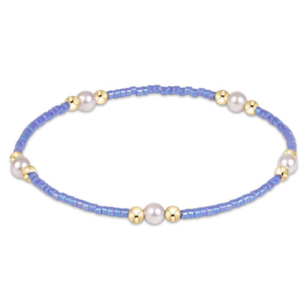 A delicate beaded bracelet with light blue seed beads, white pearl-like beads, and small gold spacer beads, shown on a plain white background.