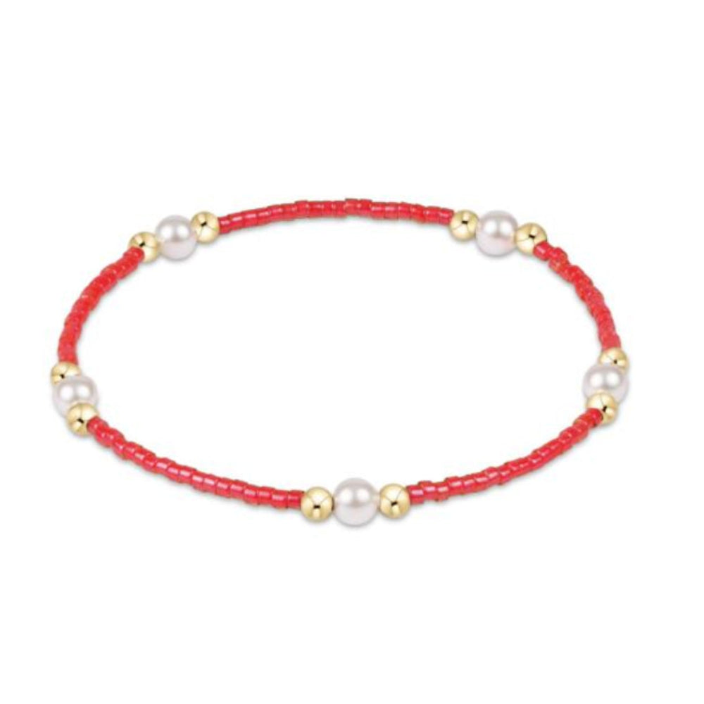 Bracelet with red beads, white pearls, and gold accents on a white background